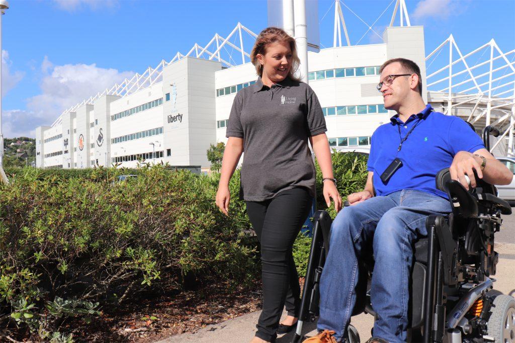 Carer walking with client outside the liberty stadium.